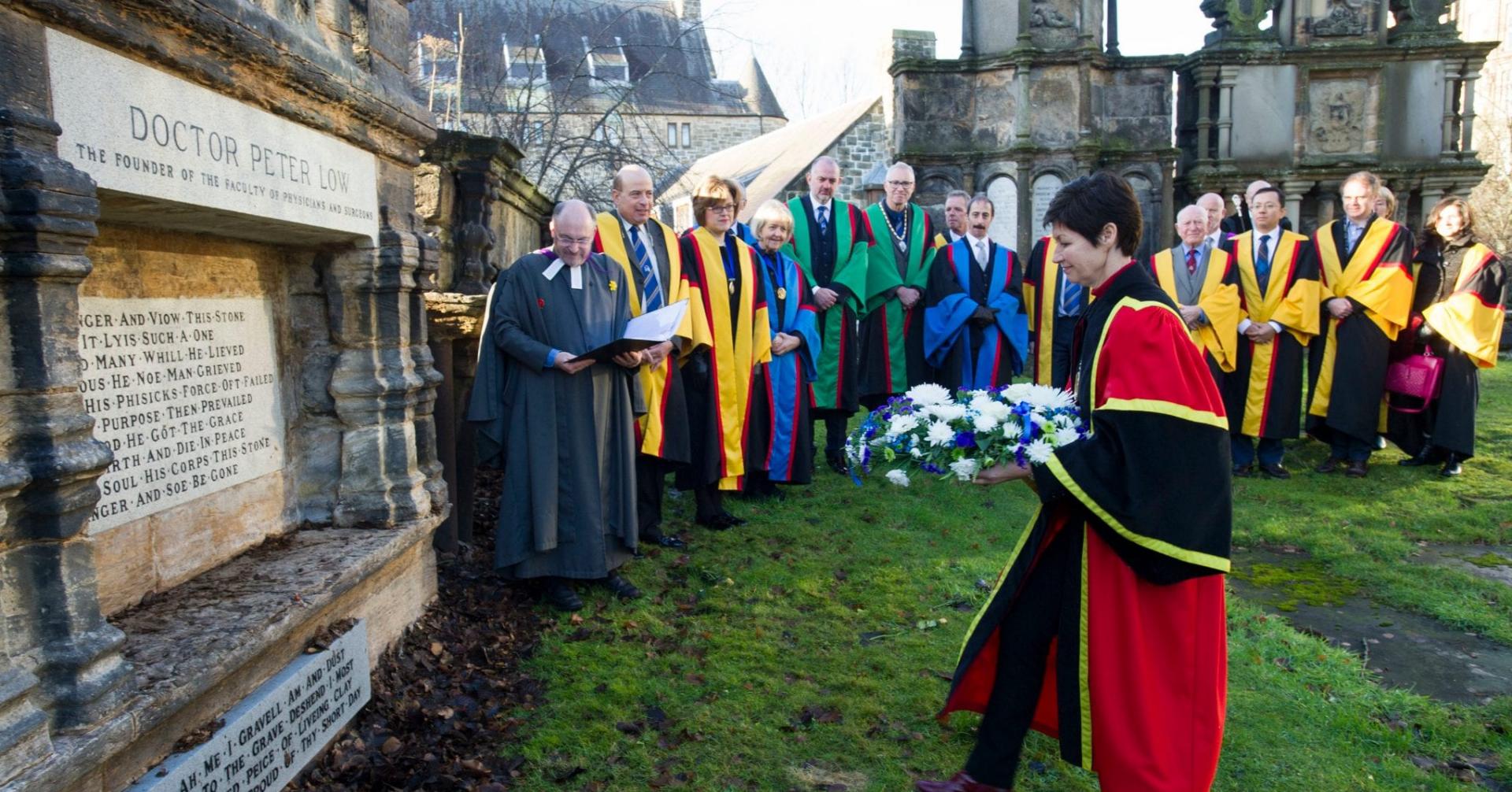 a person laying a wreath at a headstone